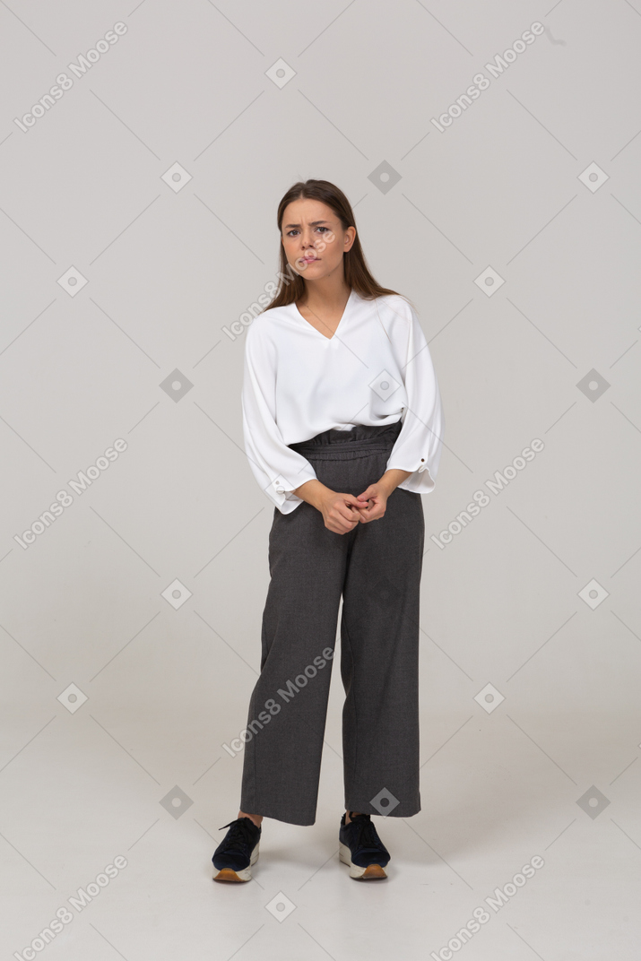 Front view of a worried young lady in office clothing holding hands together