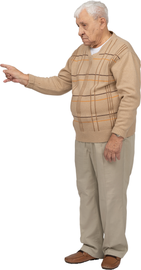 Vista lateral de un anciano con ropa informal señalando con el dedo