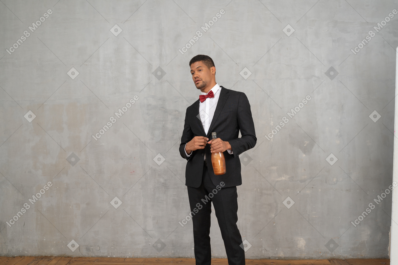 Homem de terno e gravata borboleta em pé com uma garrafa na mão