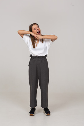 Front view of a yawning young lady in office clothing touching chin