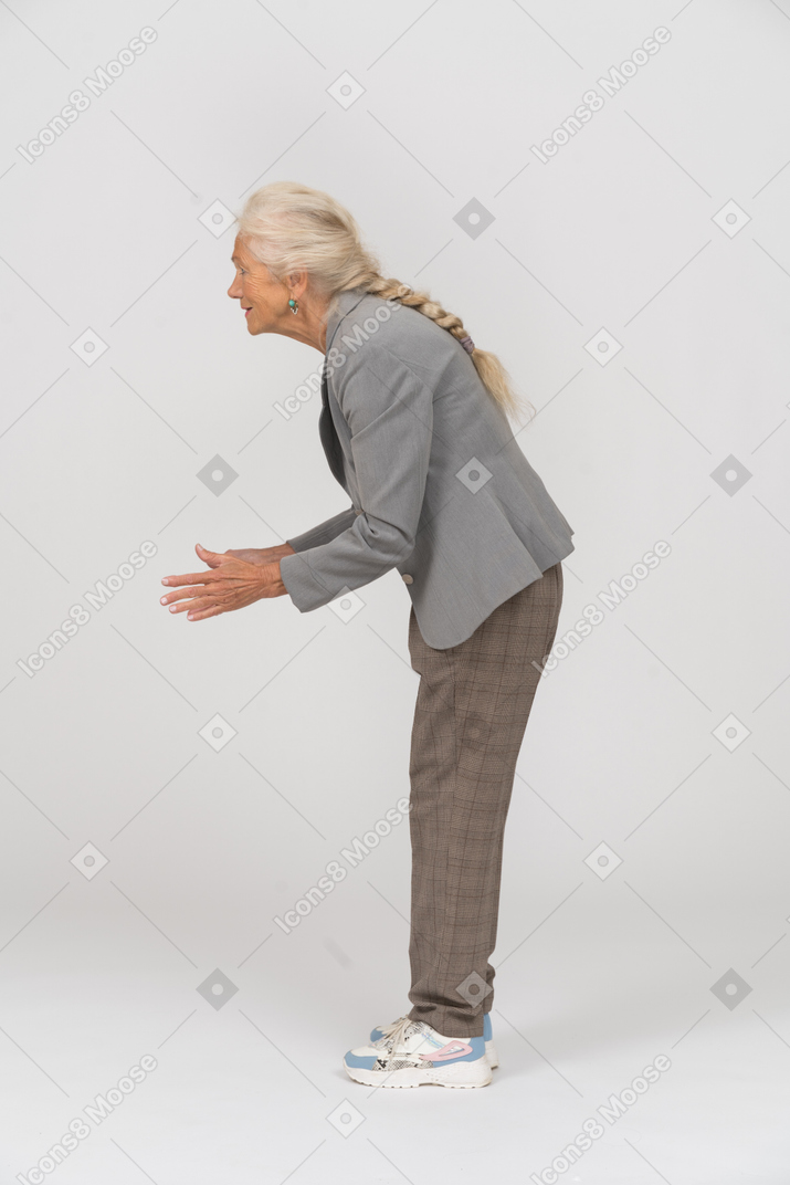 Side view of a happy old lady in suit bending down and gesturing