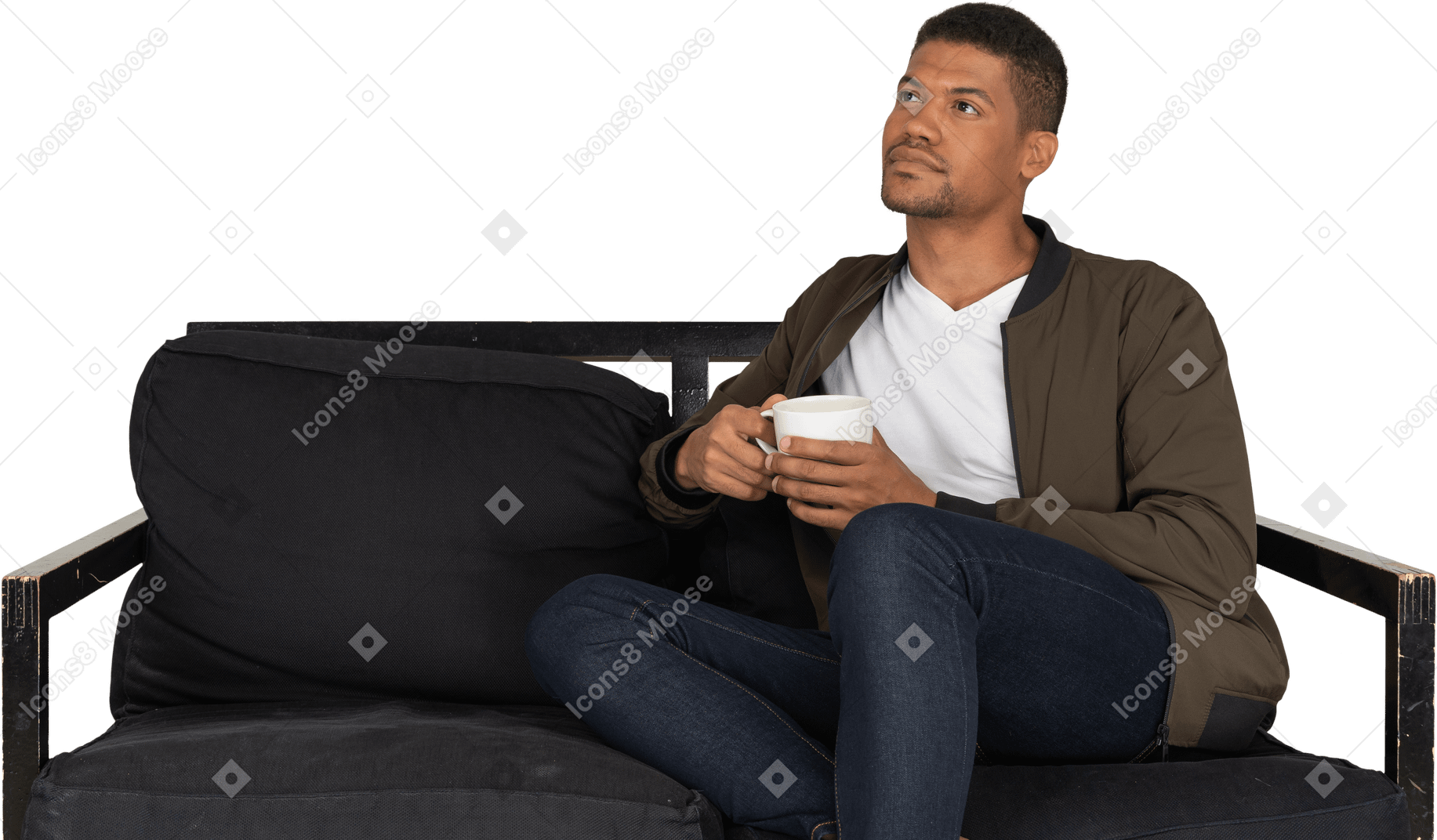 一个年轻的梦想男人坐在沙发上，喝着一杯咖啡的前视图