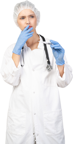 Вид спереди взволнованной молодой женщины-врача со стетоскопом, держащей термометр