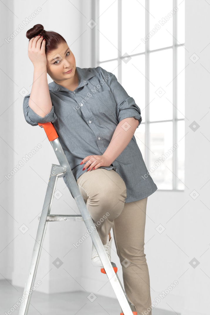 A woman sitting on a ladder in a room