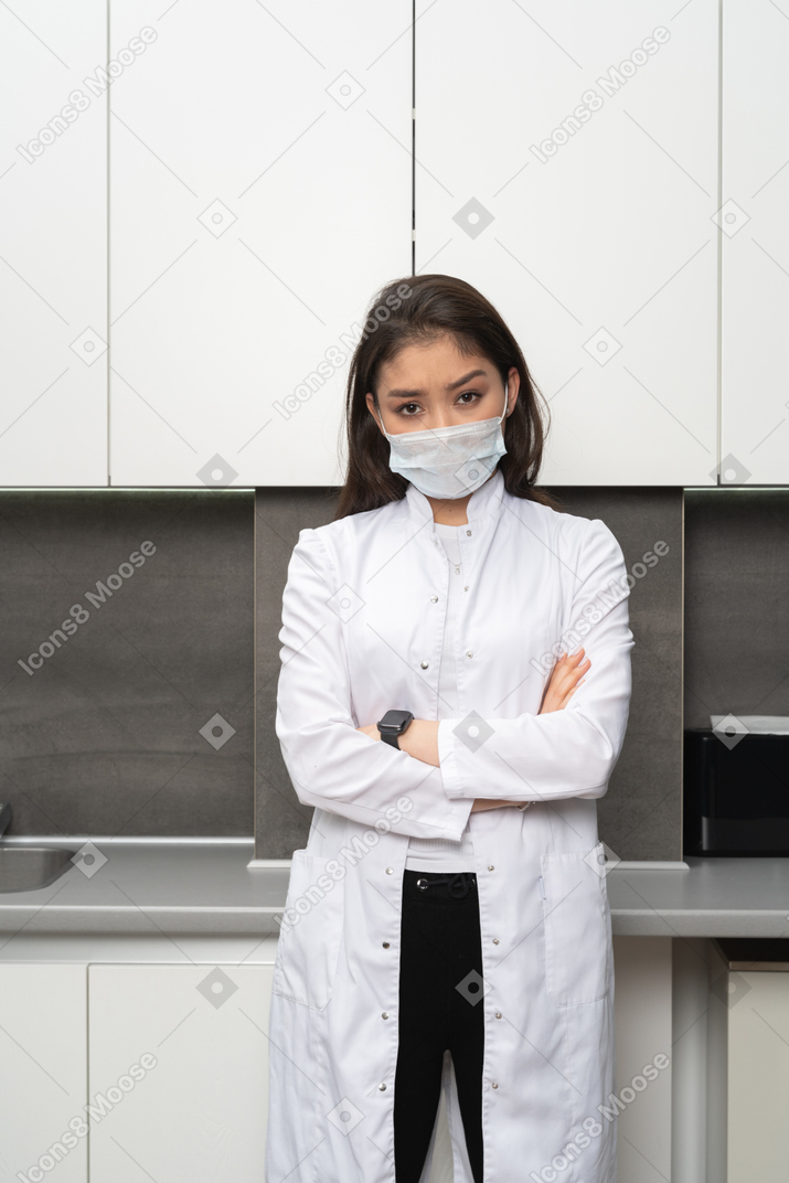 Front view of a doubtful female doctor crossing hands and looking at camera