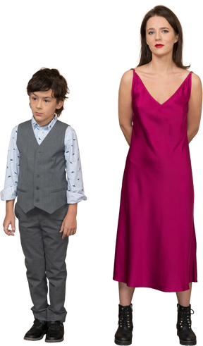 Woman in red dress holding arms behind back while boy standing near her