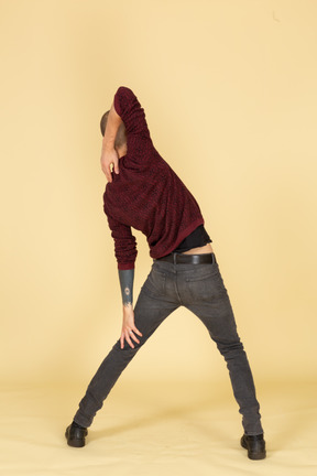 Vista posteriore di un giovane uomo in pullover rosso che allunga il braccio
