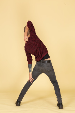 Back view of a young man in red pullover stretching his arm