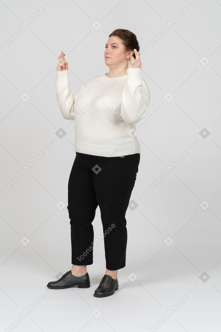 Side view of a plus size woman in casual clothes crossing fingers