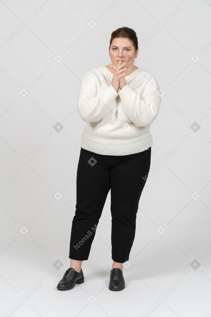 Femme dodue réfléchie dans des vêtements décontractés regardant la caméra