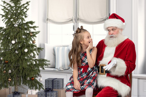 Bambina sulle ginocchia di babbo natale