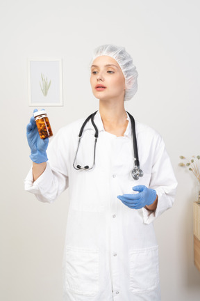 Vista frontal de una joven doctora sosteniendo un frasco de pastillas