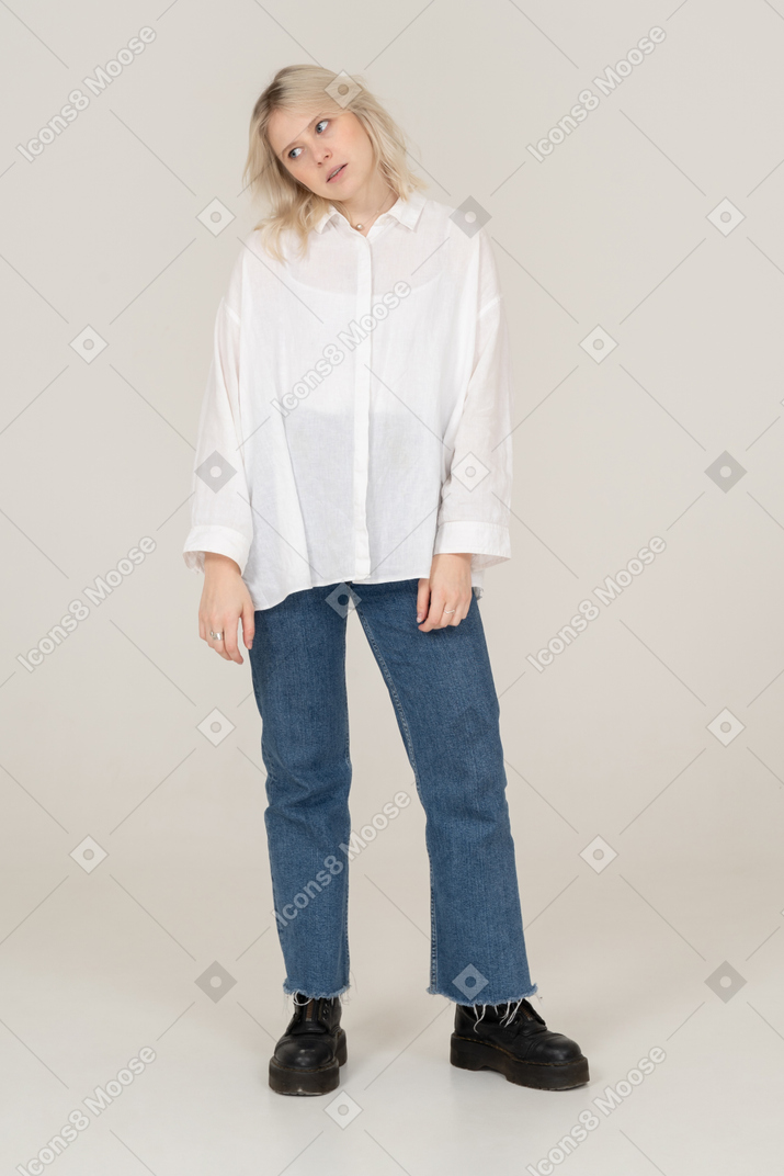 Front view of a blonde bored female in casual clothes standing and looking aside