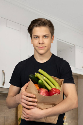 A man holding a paper bag full of vegetables