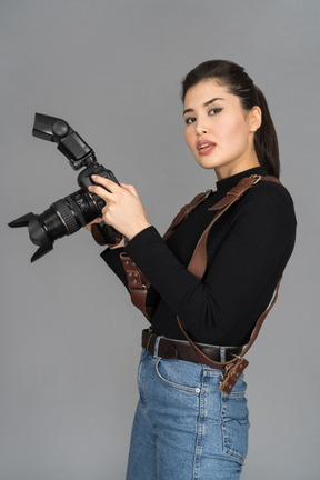 Jovem mulher segurando uma câmera enquanto posava para uma foto