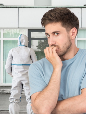 Scared young guy standing behind a man in a protective suit