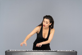 Vue de face d'une jeune femme en robe noire jouant du piano