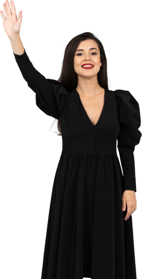Vista frontal de un saludo sonriente señorita en un vestido negro