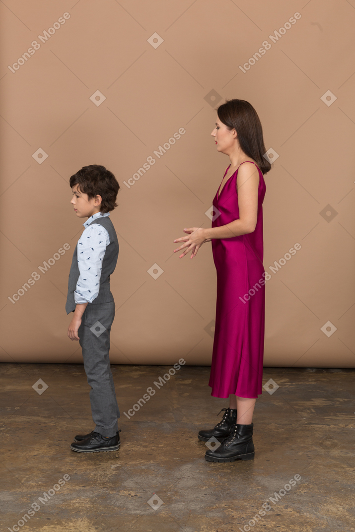 赤いドレスの若い女性とじっと立っている男の子