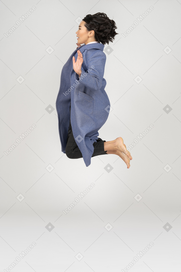 女人用折叠腿跳跃的侧视图