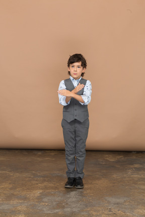 Вид спереди на симпатичного мальчика в сером костюме со знаком "стоп"