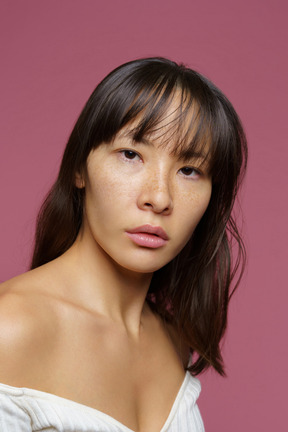 Three-quarter view of a middle-aged woman  with bare shoulder looking at camera