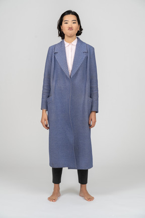 Vista frontal de una mujer gruñona con abrigo azul