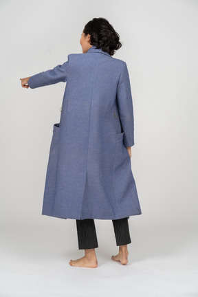 Rear view of a woman in coat pointing her finger