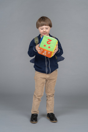 Niño pequeño con una mochila sosteniendo dados de peluche