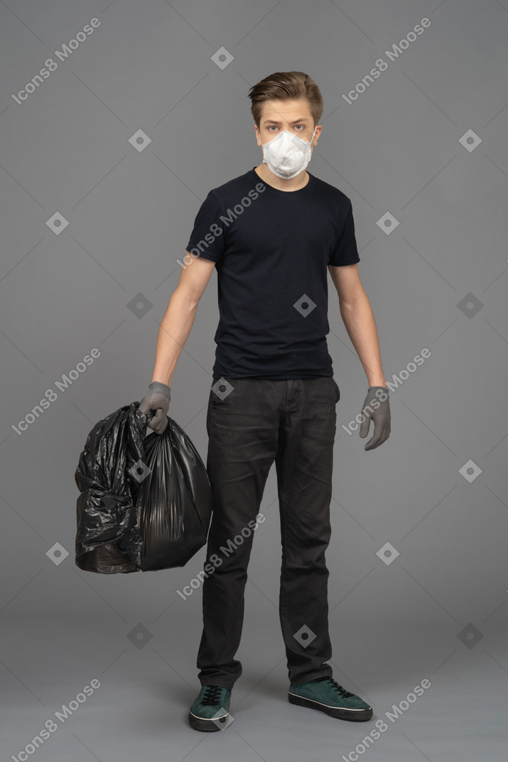 A man wearing mask and gloves while holding a trash bag