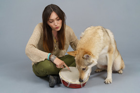 Comprimento total de uma dona e seu cachorro cheirando um tambor