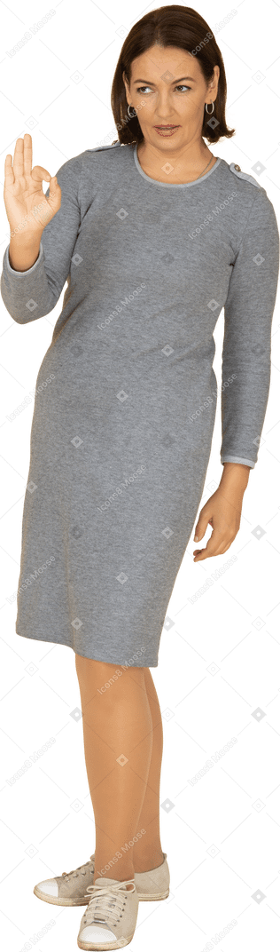 Vista frontale di una donna in abito grigio che mostra segno ok