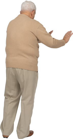 Rear view of an old man in casual clothes showing stop gesture