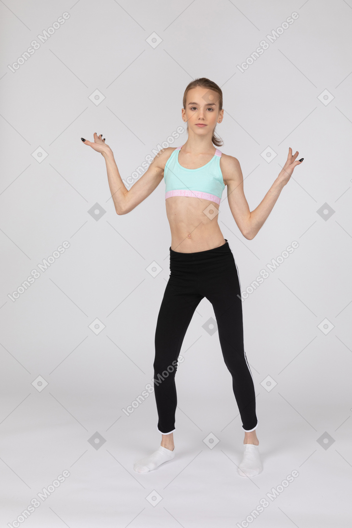 Vista frontale di una ragazza adolescente in abiti sportivi alzando le mani e ballando