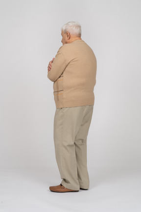 Side view of an old man in casual clothes hugging himself