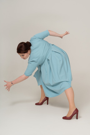 Side view of a woman in blue dress squatting