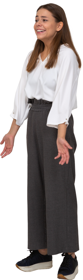Vista di tre quarti di una giovane donna ridente in abiti da ufficio che allarga le braccia