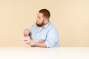 Grande homem sentado à mesa e segurando a lancheira