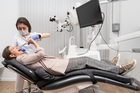 A figura intera di una dentista donna che estrae il dente del suo paziente in un armadietto dell'ospedale