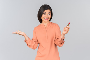 Femme indienne en haut orange portant du rouge à lèvres et tenant un
