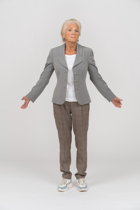 Vista frontal de una anciana en traje mirando a la cámara y gesticulando