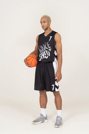 Three-quarter view of a young male basketball player holding a ball