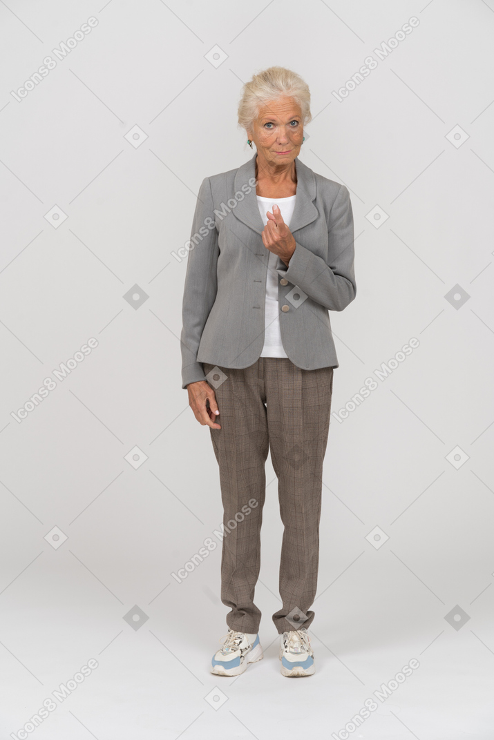 Front view of an old lady in suit looking at camera and pointing with finger
