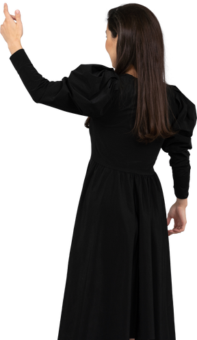 Back view of a young lady in a black dress raising her hand