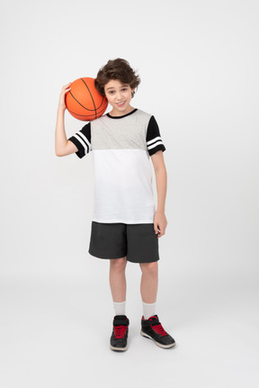 Boy holding basketball ball on his shoulder