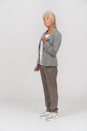 Vista lateral de uma senhora idosa de terno mostrando o punho