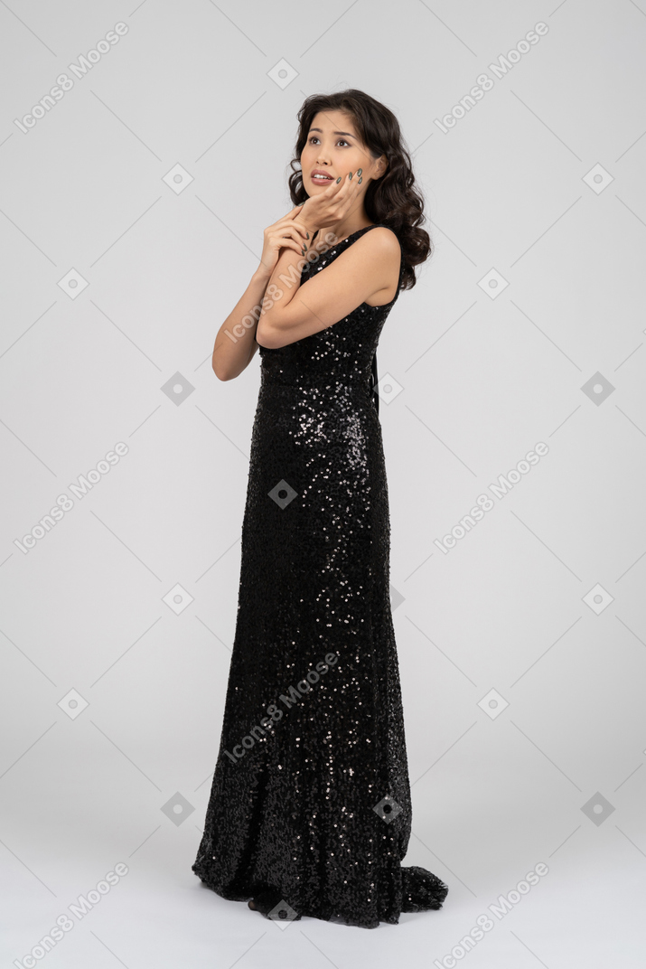 Donna in abito da sera nero in piedi nel profilo per fotocamera