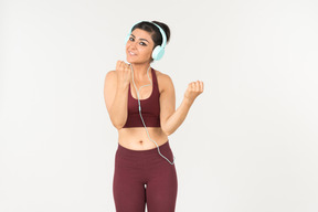 Feliz busca joven mujer india en ropa deportiva escuchando música en auriculares