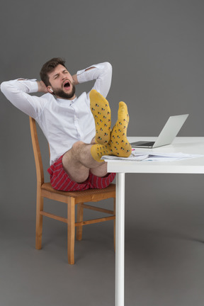 Joven cansado que bosteza en su escritorio