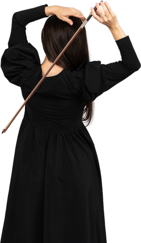 Vista de trás de uma jovem de vestido preto segurando o arco atrás